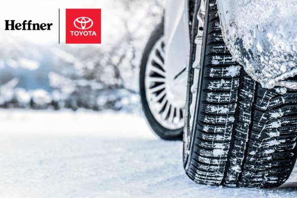 A close up of winter tires on a Toyota as it sits on snow