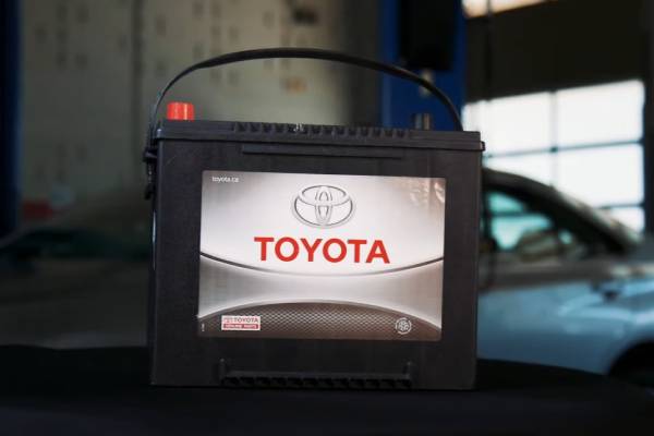 A genuine Toyota brand car battery sits on a table in an automotive workshop
