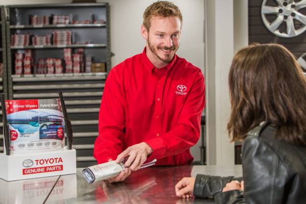 A friendly Toyota employee works the Toyota Genuine Parts desk and assists a customer