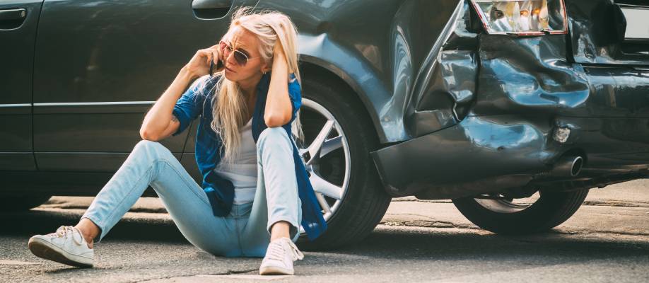 girl sits on the road, near the broken car and calls on the phone, calling for help.