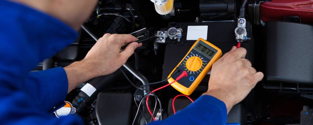 a technician tests a vehicle's battery