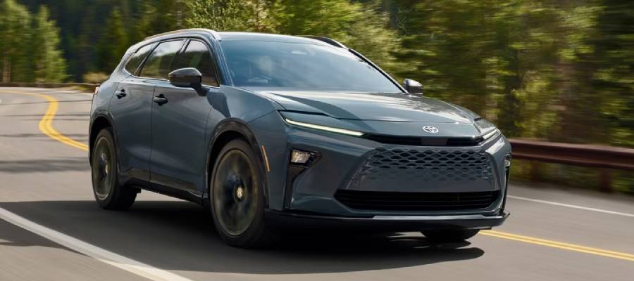 A blue 2026 Toyota Crown Signia drives along a road bordered by trees. New 2026 Toyota Crown Signia for sale at Heffner Toyota in Kitchener, ON.